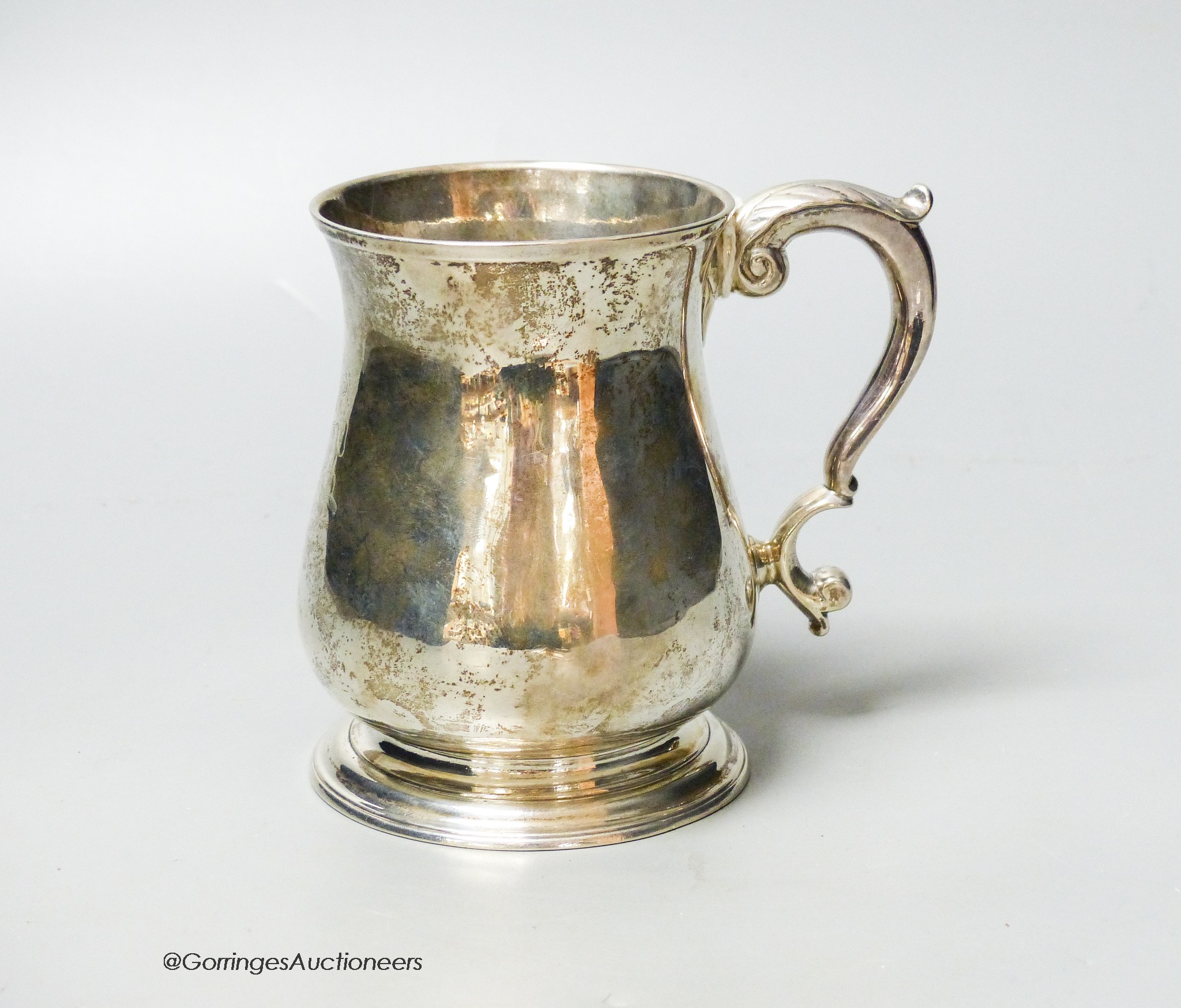 A George II silver baluster mug, with acanthus leaf capped handled and engraved crest, Henry Brind, London, 1743, height 11.7cm, 11.5oz.